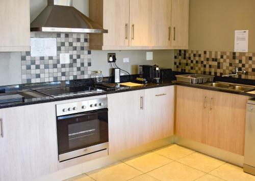 a kitchen with wooden cabinets and a stove top oven at Stonehill River Lodge by Dream Resorts in Buffeljagsrivier