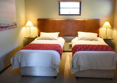 two beds in a hotel room with two lamps at Stonehill River Lodge by Dream Resorts in Buffeljagsrivier