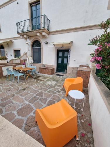 eine Terrasse mit orangefarbenen Stühlen und Tischen vor einem Gebäude in der Unterkunft Le petit refuge in Capraia