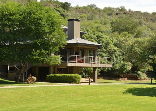 a large house on a hill with a tree at Stonehill River Lodge by Dream Resorts in Buffeljagsrivier
