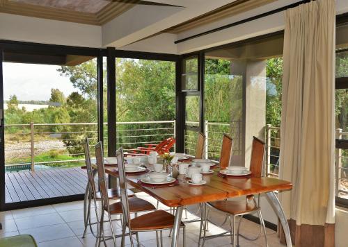 a dining room with a wooden table and chairs at Stonehill River Lodge by Dream Resorts in Buffeljagsrivier