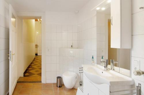 a white bathroom with a sink and a mirror at Villa Fokken Kapitänsquartier in Esens