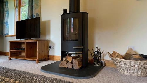a living room with a wood stove and a tv at Kerrowdown Cottage-Self Catering for 4 in the Highlands in Drumnadrochit
