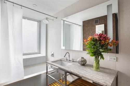 a bathroom with a sink and a vase of flowers on a counter at Beautiful 2BD near Times Square with Doorman and Gym in New York