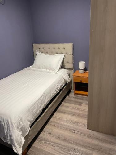 1 dormitorio con 1 cama y mesita de noche con colcha blanca en Illary Hoteles, en Pozo Almonte