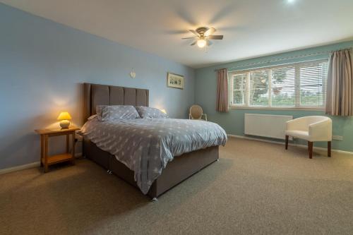 a bedroom with a bed and a chair and a window at Southview Annexe in Sculthorpe