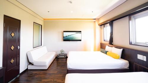 a hotel room with two beds and a chair at Rycom Crystal Hotel in Okinawa City