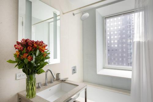 a bathroom with a sink and a vase of flowers at Stylish 1BD near Bryant Park with Washer and Dryer in New York