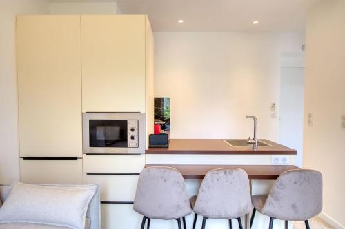 a kitchen with three chairs and a counter with a microwave at LimeSTAY - The Cannois T2 Modern WIFI in Cannes