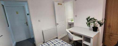 a small white room with a desk with a potted plant at White House Ensuite double bedroom in Warrington