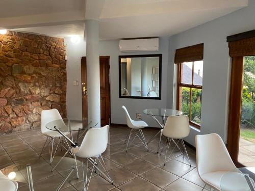 una sala da pranzo con tavolo in vetro e sedie bianche di Manzi Villa a Hartbeespoort