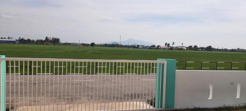 um portão em frente a um campo com um campo em De'Bendang Homestay Pendang em Pendang
