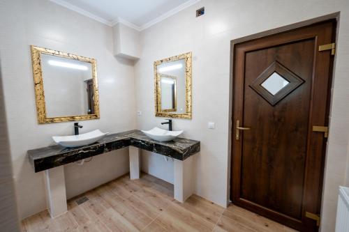 a bathroom with two sinks and a wooden door at Evergreen Chalet in Avrig