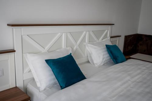 a bedroom with a white bed with blue pillows at Evergreen Chalet in Avrig