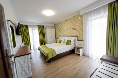 a bedroom with a large bed with green curtains at Evergreen Chalet in Avrig