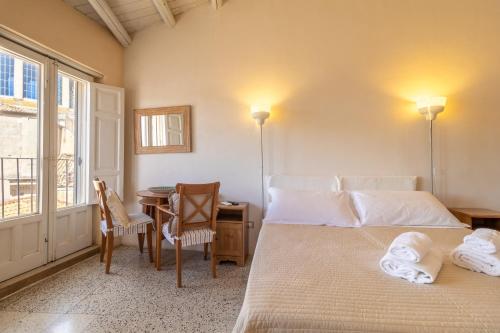 a bedroom with a bed and a table and a window at Caelum Hyblae in Ragusa