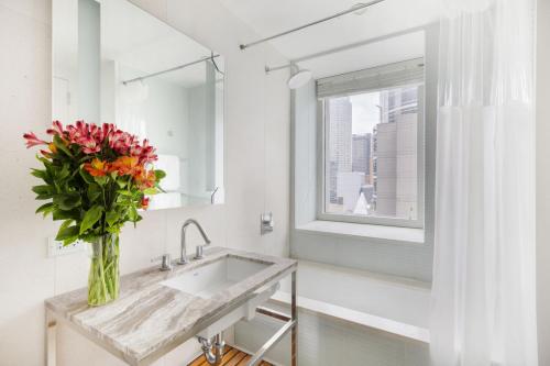 a bathroom with a sink and a vase of flowers at Stylish 2BD with Washer and Dryer near Times Square in New York
