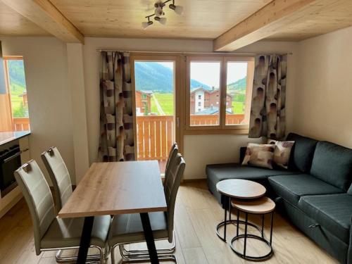 ein Wohnzimmer mit einem Sofa und einem Tisch mit Stühlen in der Unterkunft Sporthotel Oberwald in Oberwald