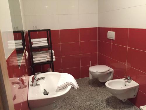 a red and white bathroom with a toilet and a sink at Casa Lampone in Trento