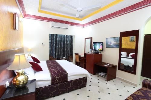 a hotel room with a bed and a television at Al Bahjah Hotel in Seeb