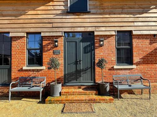 two benches in front of a brick house with a door at The Old Stables in Salisbury