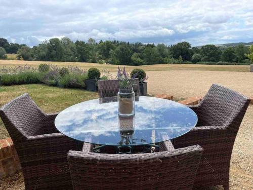a glass table with two chairs and a drink on it at The Old Stables in Salisbury