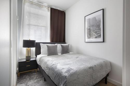 a white bedroom with a bed and a window at Perfectly located 2BD near Times Square with Gym in New York