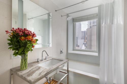 a bathroom with a sink and a vase of flowers at Perfectly located 2BD near Times Square with Gym in New York