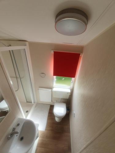 uma casa de banho com um WC e um tecto vermelho em Fantasy Island King Fisher 8Berth 401 em Ingoldmells