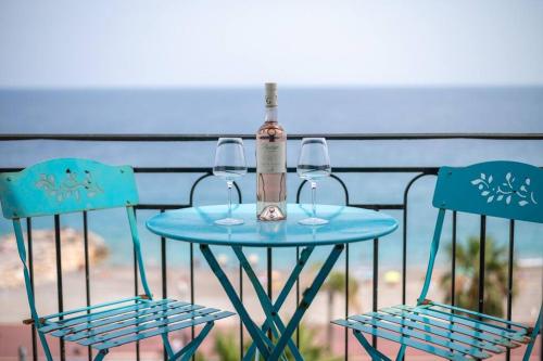 une table avec deux chaises, une bouteille et deux verres dans l'établissement Le balcon de la baie des Anges, à Nice