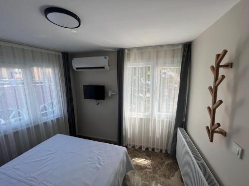 a bedroom with a bed and a tv and two windows at Ada Antik 2 in Adalar