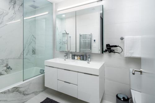 a white bathroom with a sink and a shower at Chic and Spacious 2BD Apt with washer and dryer in unit in New York