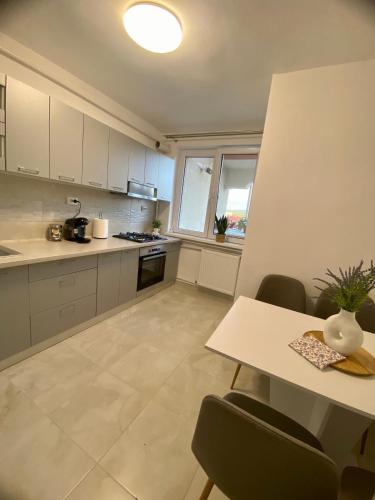 una cocina con armarios blancos y una mesa con sillas. en Floris Apartments, en Beclean