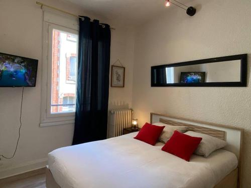ein Schlafzimmer mit einem weißen Bett mit roten Kissen und einem Fenster in der Unterkunft F2 Résidence Eurotel n°1 avec vue sur le Cher, Centre - Ville in Montluçon