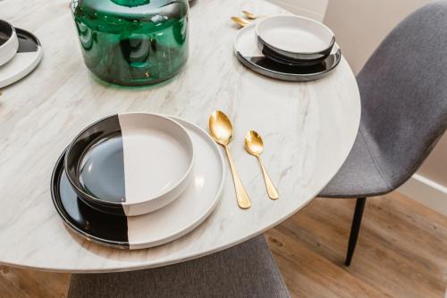 a white table with gold spoons and plates on it at VICHY - The Glass House VIP Luxury Stay with gym, Cinema & Gaming Rooms, and Work space access in Hull