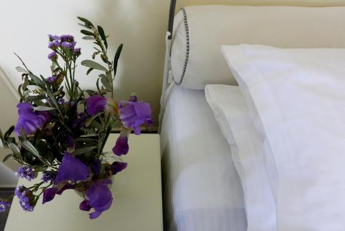 a vase of purple flowers sitting next to a bed at KEOS by the sea in Korissia