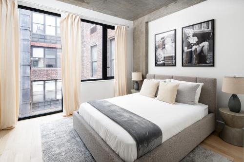 1 dormitorio con 1 cama grande y ventanas grandes en Perfectly located 2BD Penthouse in Chelsea en Nueva York