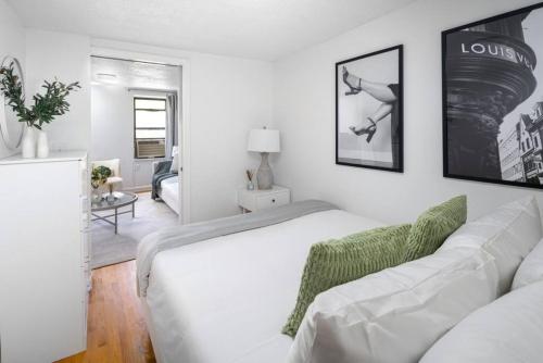 a white bedroom with a bed and a living room at Stylish One-Bedroom with In-unit Laundry in East Village in New York