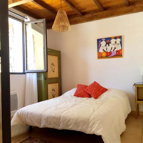 a bedroom with a bed with white sheets and red pillows at Maison confortable avec piscine à Saint-Julien-de-la-Nef in Saint-Julien-de-la-Nef