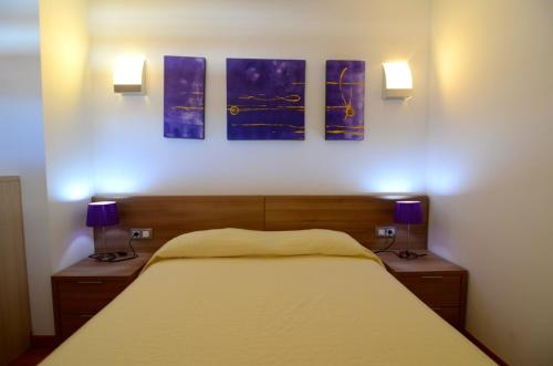 レスカラにあるApartamentos Graciaのベッドルーム1室(壁に絵画3点が飾られたベッド1台付)