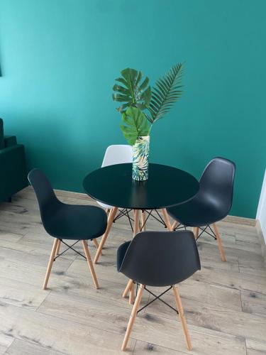 a table with four chairs and a vase with a plant on it at Blue Apartment close to Old Town in Bydgoszcz
