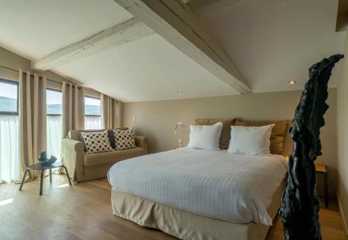 a bedroom with a large bed and a couch at Art'Hotel & SPA Le Potin Gourmand in Cluny