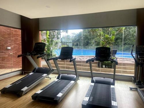 a gym with three treadmills and a large window at Modern Apartment in WP Putrajaya in Putrajaya