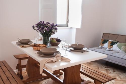 una mesa de comedor con platos y flores. en Casa Quintal da Aldeia en Alcobaça