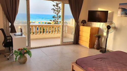 una camera da letto con balcone affacciato sull'oceano di Stunning 5-Bedroom Villa with Breathtaking Sea Views & Roof Penthouse at Badr resort North Coast El Alamein !! الساحل الشمالي a El Alamein
