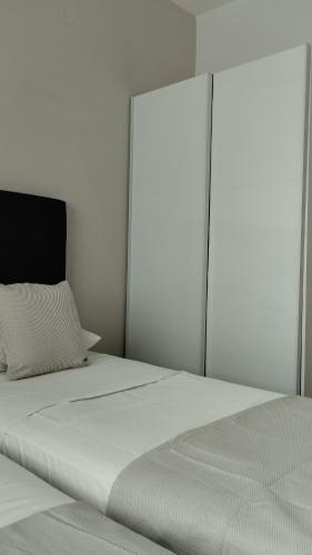a white bedroom with a large white bed with a headboard at inas apartments 2 in Lefkímmi