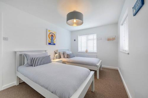 a white room with two beds and a window at Shore House - Walton in Walton-on-the-Naze