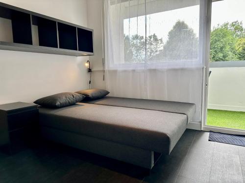 Bett in einem Zimmer mit einem großen Fenster in der Unterkunft Happy Studio terrace in Schiltigheim