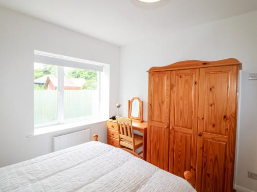 ein Schlafzimmer mit einem Bett, einer Kommode und einem Fenster in der Unterkunft Ahiohill Meadows 