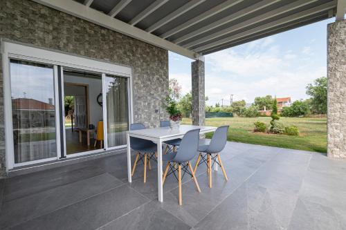 a patio with a white table and chairs on it at Topos Maisonettes by RentalsPro - Kalives Halkidiki in Kalivia Poligirou